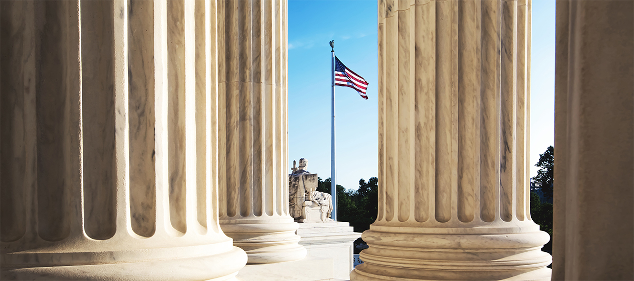 Image of the US Flag amidst government building columns