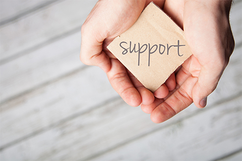 Image of hands holding a sign reading "Support"
